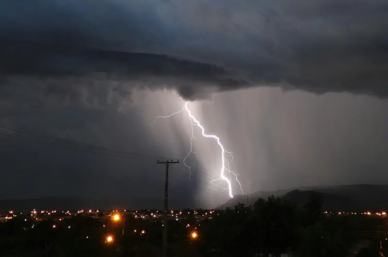 Hurricane passing over a city with a lightning strike in the foreground